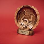 Troféu de premiação musical dourado diante de um fundo vermelho