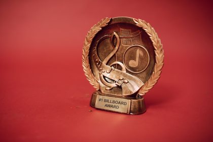 Troféu de premiação musical dourado diante de um fundo vermelho
