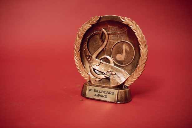 Troféu de premiação musical dourado diante de um fundo vermelho