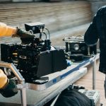 Equipamentos profissionais de filmagem em um set de cinema, com integrantes da equipe se preparando para gravar