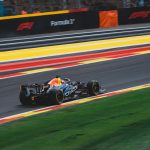 Carro de Fórmula 1 em alta velocidade no circuito de Spa-Francorchamps, na Bélgica, durante um dia ensolarado de corrida.